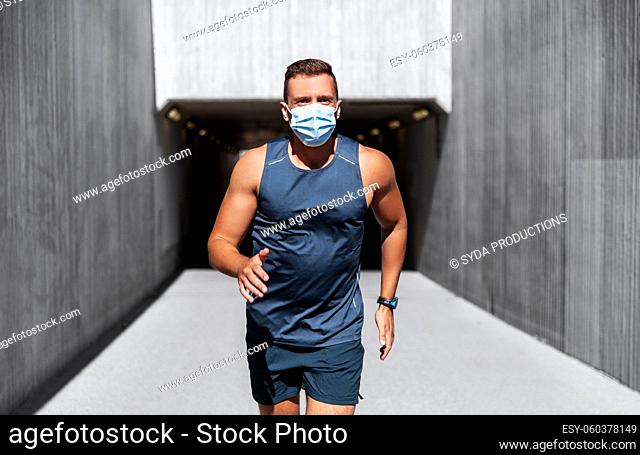 young man in medical mask running outdoors