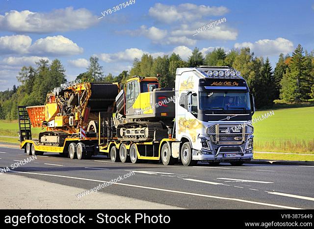 Customised Volvo FH16 750 truck with paintings and bull bar of Moto-Olli Oy hauls heavy machinery on highway. Salo, Finland. September 19, 2020
