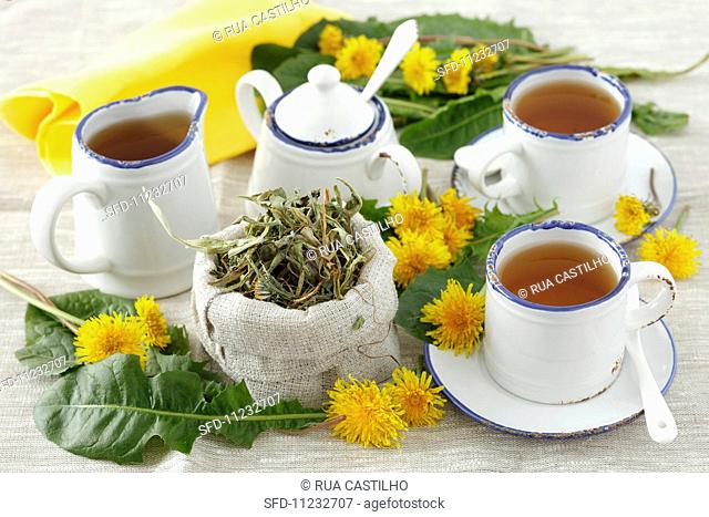 Three cups of dandelion tea, tea leaves and fresh dandelions