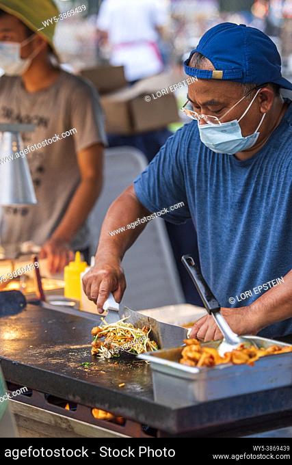 A food vendor makes stir fried vegetables with chicken at the county fair in Arlington, Virginia
