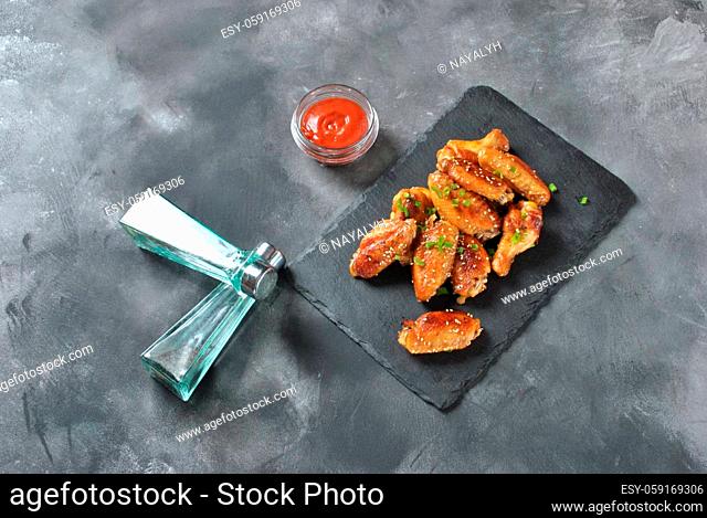 Fried barbecue chicken wings close up on wooden tray shot with selective focus