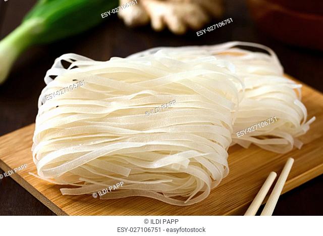 Raw rice flour noodles on wooden board, photographed with natural light (Selective Focus, Focus in the middle of the noodles)