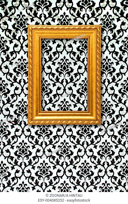 Gold frame on a black and white wallpaper