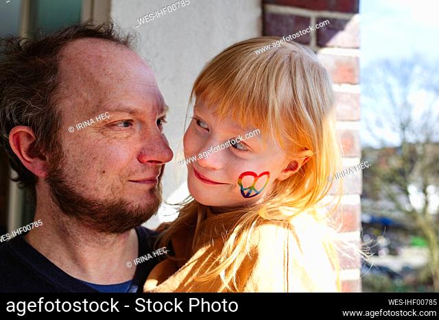 Smiling father looking at daughter with peace sticker on cheek