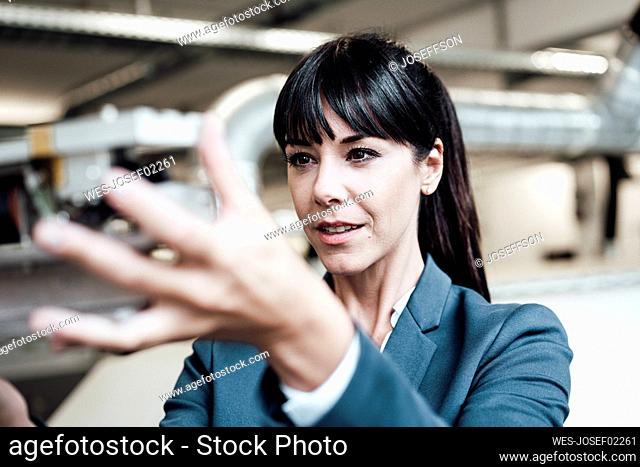 Female professional investigating machine part at industry