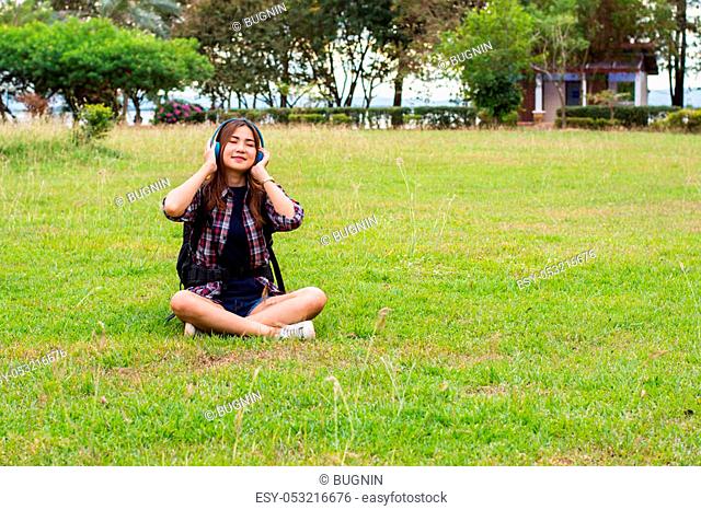 portrait of a beautiful, young woman with music sitting on grass