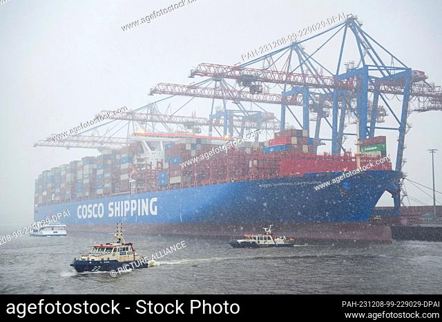 08 December 2023, Hamburg: The container ship ""Cosco Shipping Capricorn"" is loaded at the Tollerort container terminal in the Port of Hamburg during snowfall