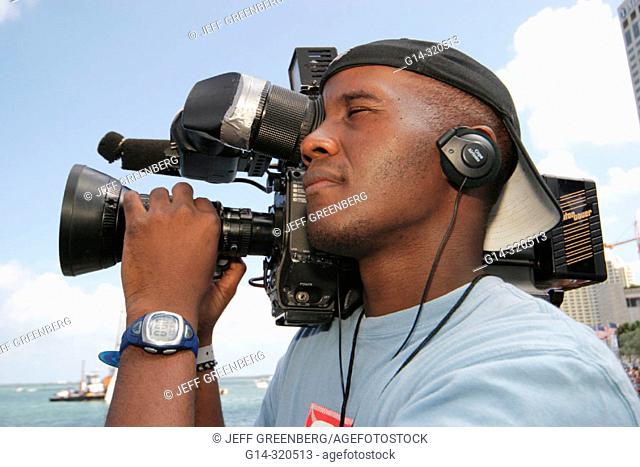 Black Hispanic TV cameraman at Red Bull Flügtag festival, Bayfront Park. Miami. Florida, USA
