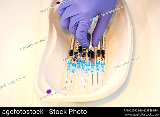 23 September 2021, Lower Saxony, Hanover: A helper places a syringe with Corona vaccine in a dish in a vaccination booth at the vaccination centre on the...