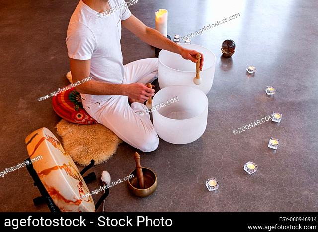 Man sitting in indian with his two big crystal bowls and his native sacred drum, playing sacred music in a meditative state. Shot from above