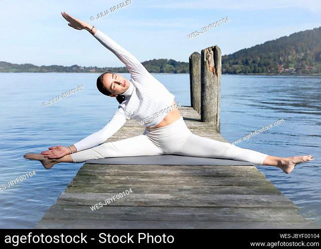 Woman stretching legs on jetty at alpine lake