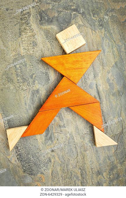 abstract of a dancing, running or walking figure built from seven tangram puzzle wooden pieces, , the artwork copyright by the photographer