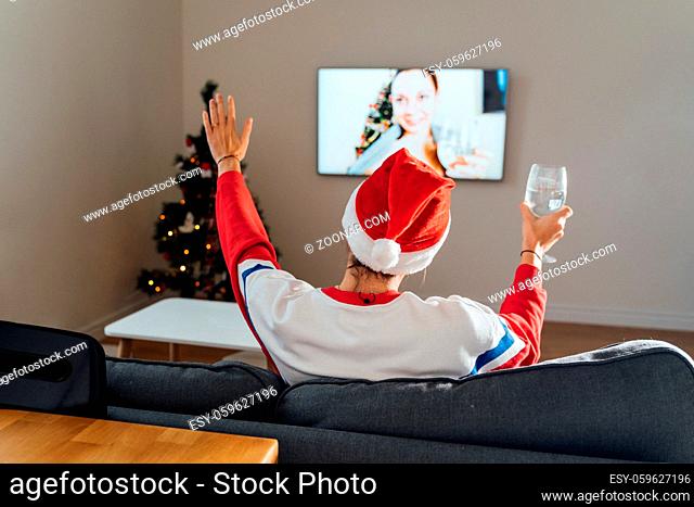 Millennial young woman using phone at home in Christmas Eve. Online holiday shopping, quarantine virtual celebration . High quality photo