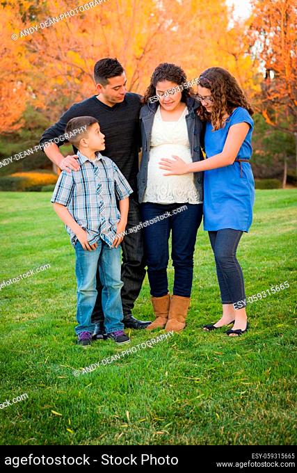 Hispanic Pregnant Family Portrait Against Fall Colored Trees