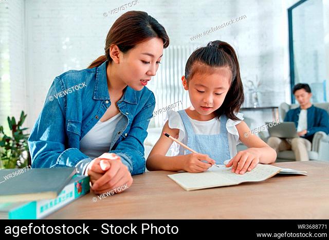 A beautiful young woman coaching daughter to do homework