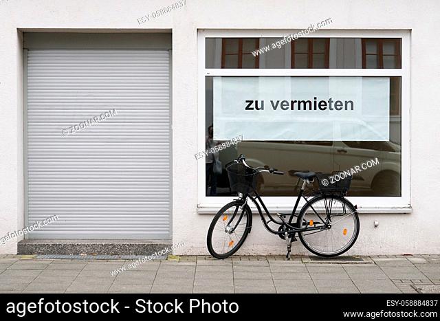 German vacancy sign in store window - zu vermieten translates as for rent or to let - bicycle parked outside closed shop
