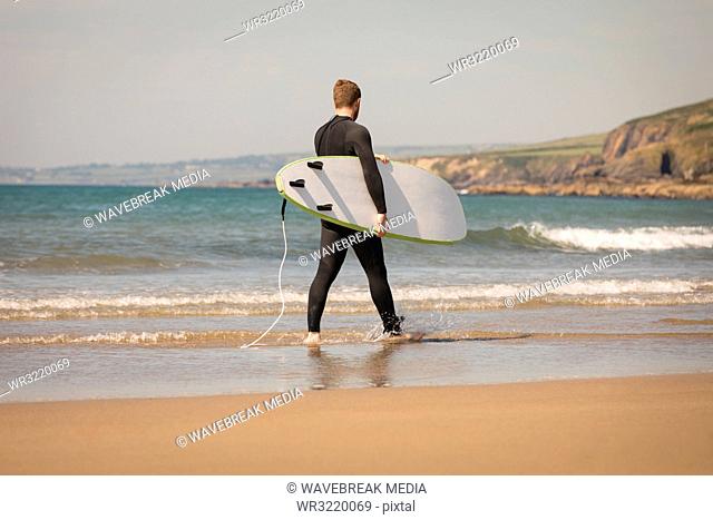 Surfer with surfboard walking at the beach