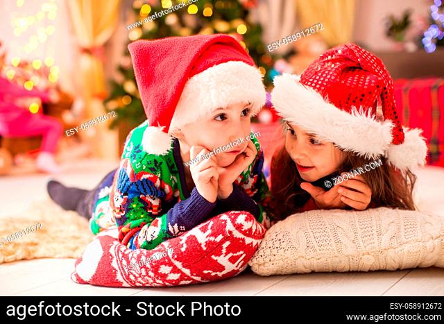 Little sister tells winter story to her brother. Children dreaming about christmas gifts. Merry Christmas and Happy Holiday
