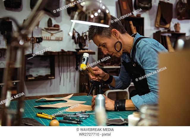 Craftswoman hammering leather