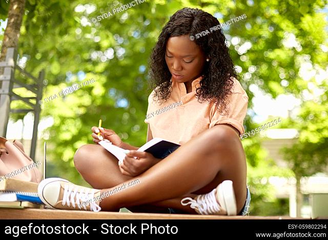 african student girl making notes in book