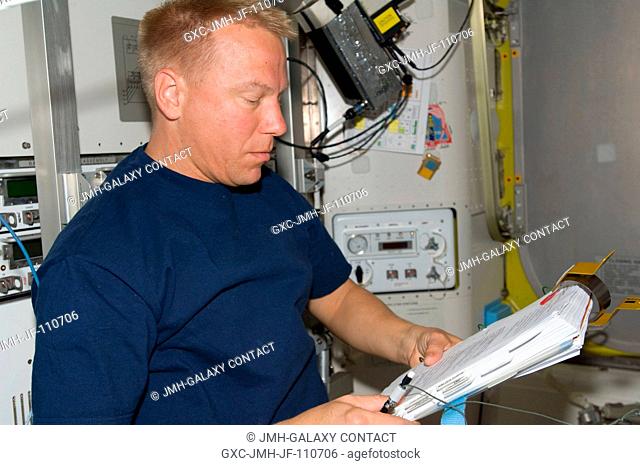 Astronaut Tim Kopra, Expedition 20 flight engineer, looks over a checklist while assisting the spacewalk preparations of astronauts Dave Wolf and Christopher...