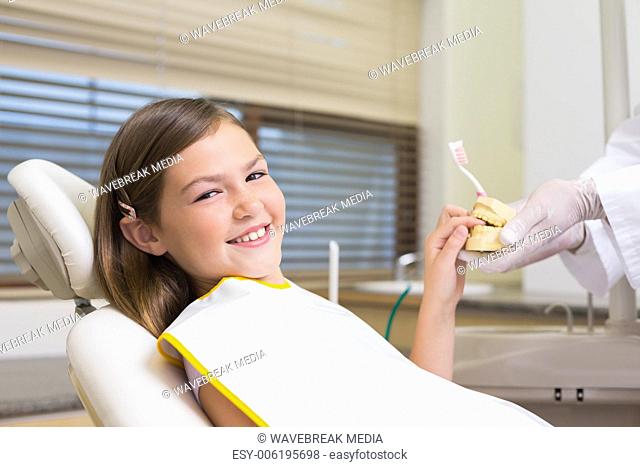 Pediatric dentist showing little girl teeth model