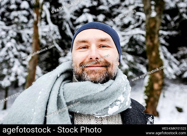 Smiling mature man wearing scarf on snow during vacations