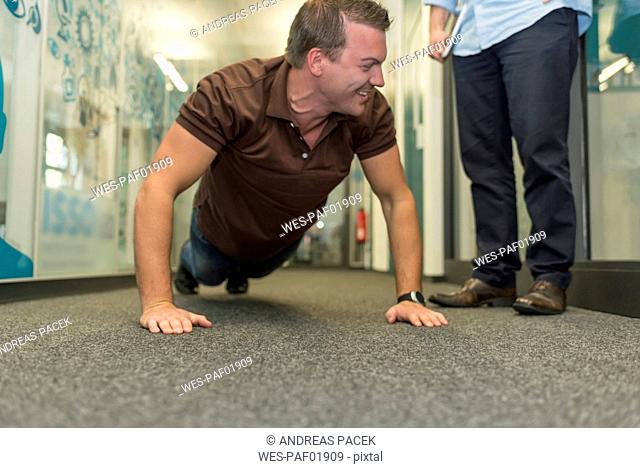 Businessman doing push-ups on office floor