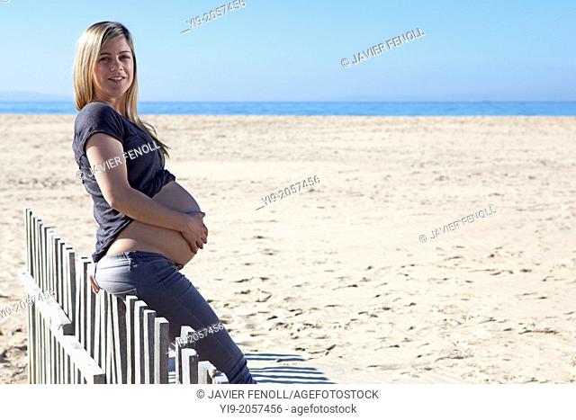 Pregnant woman sitting on wood fence
