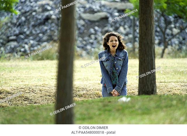Young woman sitting outdoors with mouth wide open