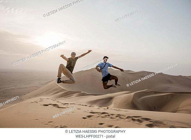 Namibia, Namib, two friends jumping in the air on desert dune
