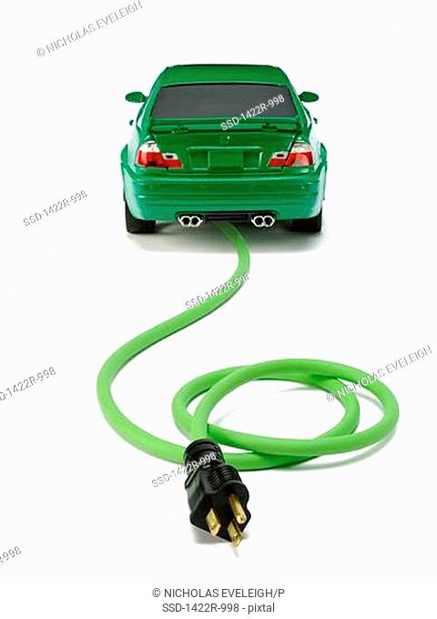 Small green automobile with a green electrical power cord and black plug