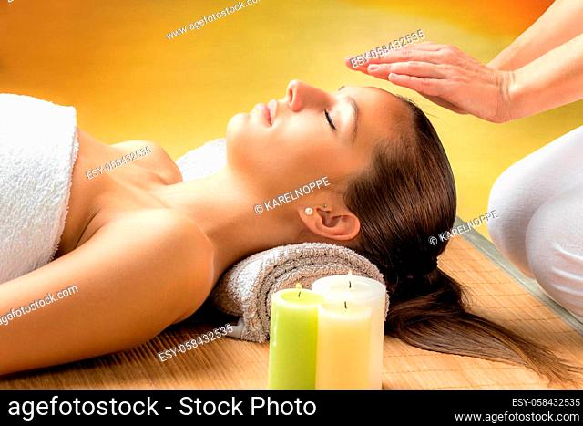Close up portrait of attractive young woman having alternative treatment therapy. Therapist’s hands on woman’s forehead