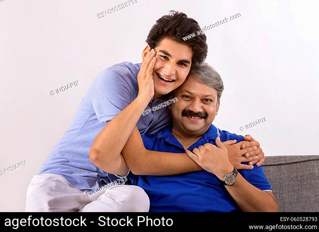 Indian father and son loving each other while sitting on sofa