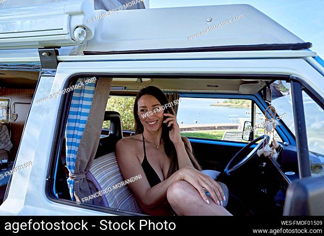 Smiling woman talking on mobile phone in motor home