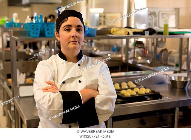 Female chef standing with arms crossed in kitchen