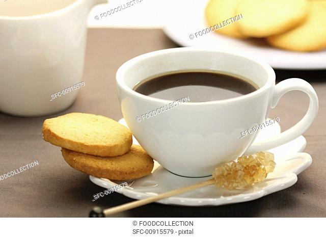 A cup of espresso with rock candy on a stick and butter cookies