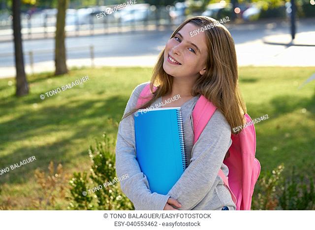 Blond kid student girl with notebook and backpack in the city back to school