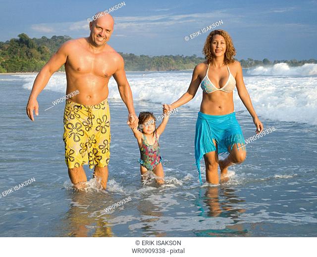 Parents playing with young daughter on beach