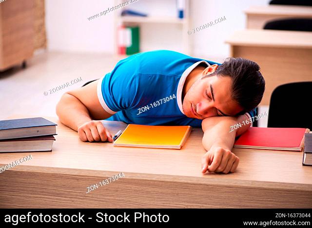 Exhausted student preparing for the exams in the classroom