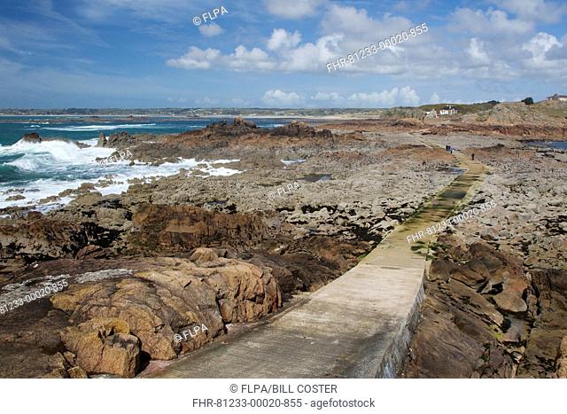 View of causeway over rocky shore at low tide, La Corbiere, St. Brelade, Jersey, Channel Islands, May