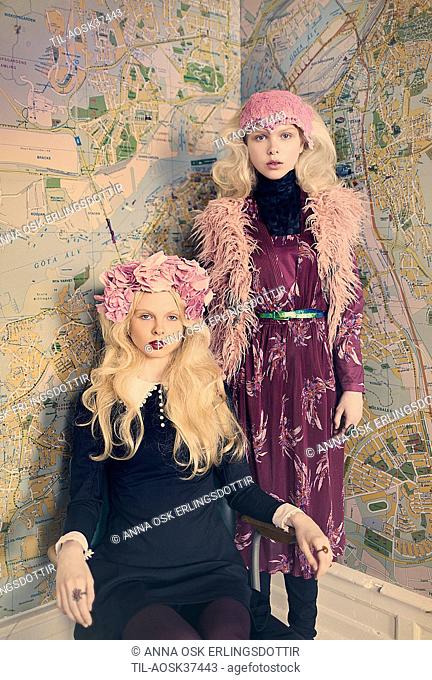 Young female figures in bohemian clothing standing beside map