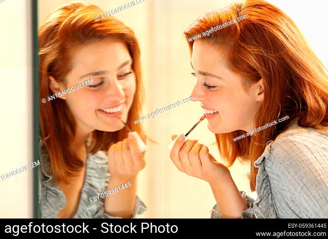 Happy woman painting lips using mirror in the bathroom