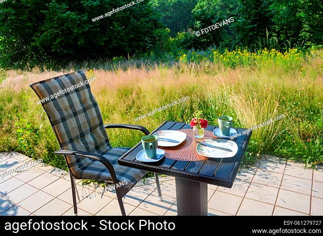 Breakfast on the terrace in front of green nature on a beautiful summer day, with cup and table