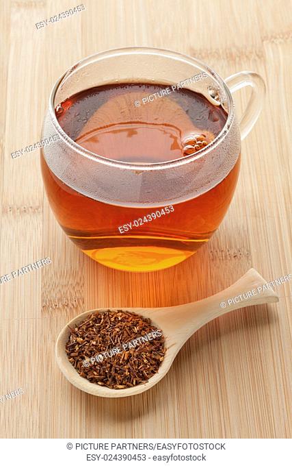 Cup with South African Rooibos tea and a spoonful dried tea