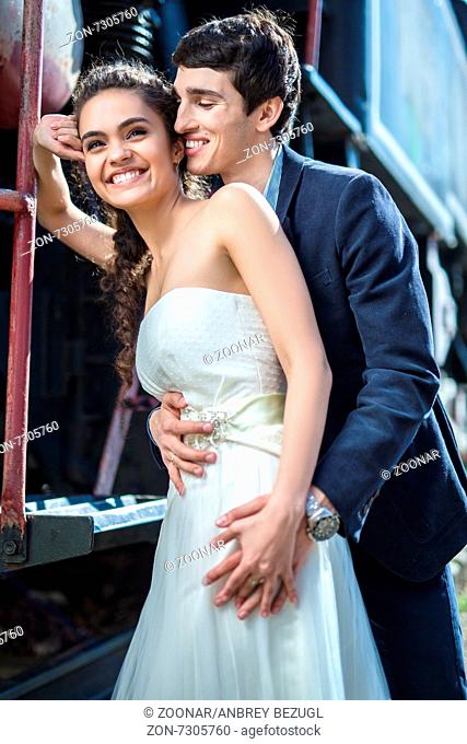 Portrait of happy wedding couple near the old steam locomotive
