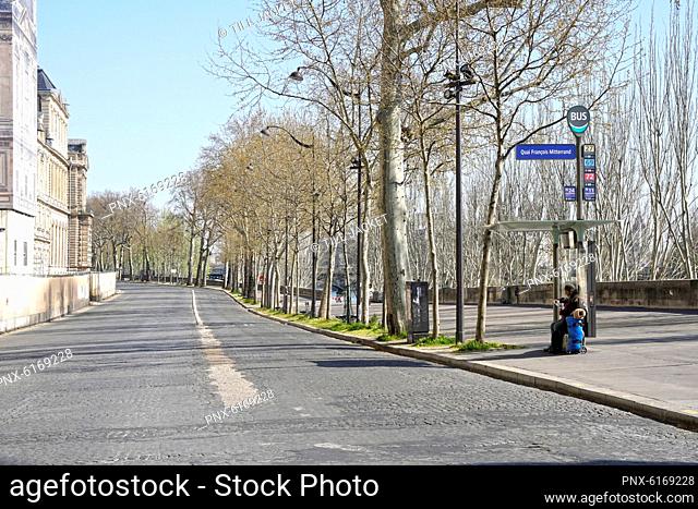 France, Paris (1st arr.) 03/25/20. Homeless seated at a bus stop, quai Francois Mitterrand completely empty following the confinement of the population to fight...