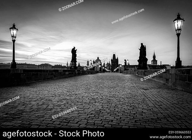 Charles Bridge at sunrise, Prague, Czech Republic. Dramatic statues and medieval towers. Unique view at dawn when there are almost no people on the bridge