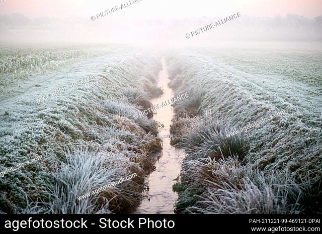 21 December 2021, Lower Saxony, Wardenburg: Fog shrouds a ditch between two fields in Oldenburg County in frigid temperatures
