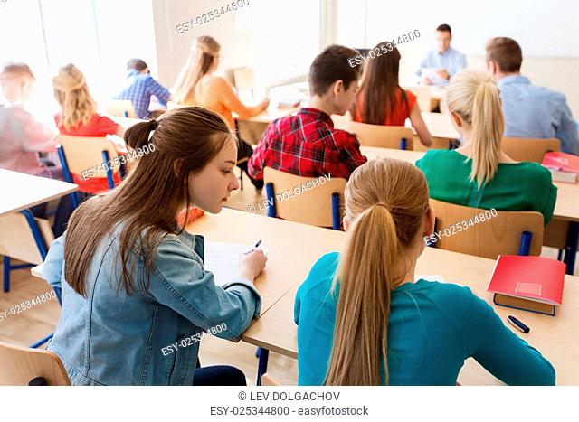education, learning, cheating and people concept - group of students writing school test